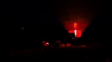 Sıcak hava balonu, uçuş için hazırlanıyor. Gece ağır çekimde otoparkta duruyor.