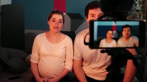 Donna incinta sul terzo trimestre e l'uomo sono seduti sul divano in soggiorno e tenere un blog — Video Stock