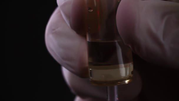 Close-up de médicos mão regulando o sistema de infusão em câmera lenta no fundo preto — Vídeo de Stock
