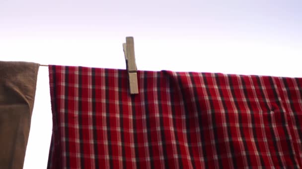 Κόκκινο πουκάμισο κρέμεται σε μια γραμμή πλυσίματος και στέγνωμα μετά πλυντήριο γυρίστηκε σε κοντινό πλάνο — Αρχείο Βίντεο