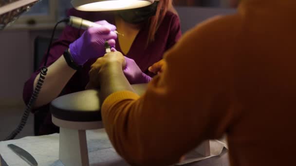 En svart man i en skönhetssalong lägger sina händer i ordning genom att göra en hårdvara manikyr — Stockvideo
