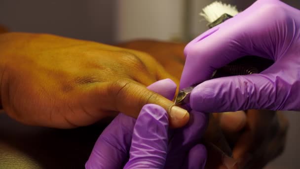 Cuticle circumcision on a afro man finger close-up using manicure tools in a beauty salon — 图库视频影像