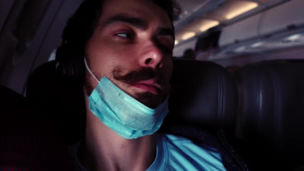Jonge mannelijke passagier wacht op de vlucht luisteren naar muziek in koptelefoon en rondkijken — Stockvideo