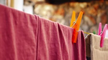 Bir erkek eli, çamaşır mandalını dışarıda kuruyan kıyafetlerden ayırır.