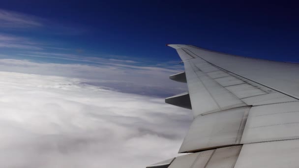 The steel wing of an airplane flying above the clouds in the blue sky — Stockvideo