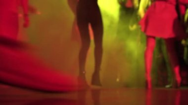 Closeup view of people legs dancing at night club among the smoke and light show