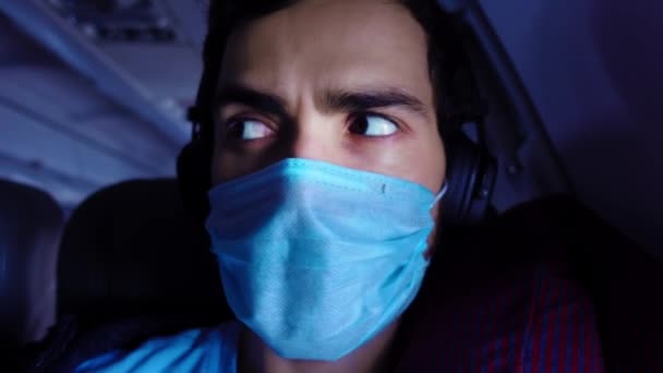 Il giovane si toglie la maschera protettiva medica e respira profondamente a bordo dell'aereo — Video Stock