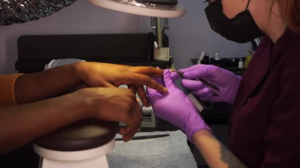戴口罩的女主人用剪切机切割黑人男性的角质层时，修指甲过程的闭合镜头 — 图库视频影像