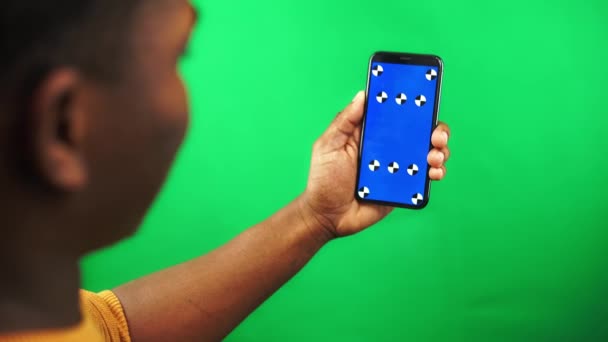 African American man håller smartphone med spårmarkör på den och sveper vänster på chroma key — Stockvideo
