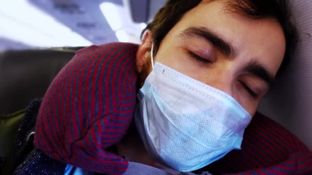 顔保護マスクの若い男が点滅していると眠りに飛行機サルーンに座って — ストック動画