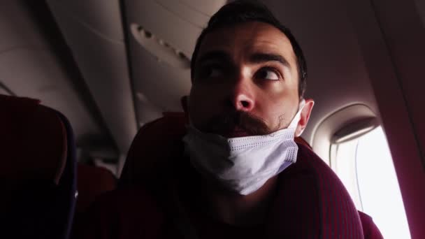 Pasażer siedzi w samolocie z maską na podbródku, gdy ktoś każe mu ją nosić. — Wideo stockowe