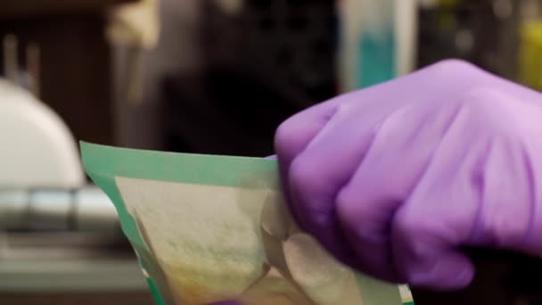 Мастер женского маникюра открывает конверт с стерильными маникюрными инструментами в спа-салоне в макро — стоковое видео