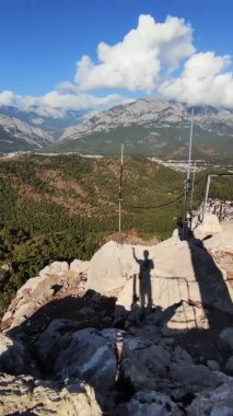 Uçurumun kenarında el sallayan ve yüksek dağın zirvesinde duran ve el sallayan adamın gölgesi.