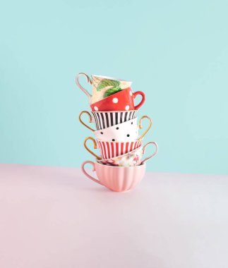 Porselen çay fincanları, pastel pembe arka plana karşı yaratıcı kompozisyon. Mutfak dekorasyonu, çay saati, çeşitli popüler alışkanlıklar..