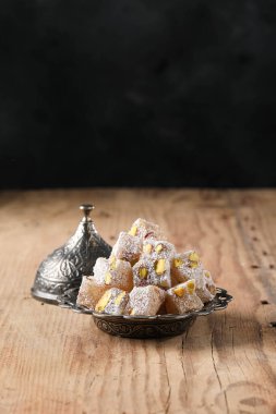 Turkish delight with pistachio in a copper plate on a wooden floor, coconut Turkish delight, text space