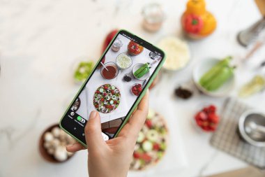 Cep telefonuyla pizza yapan kadın.