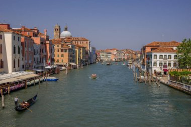 Grand sunlit channel in Venice, holiday season, gondola and a number of boats in the background of the traditional Venetian architecture