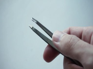 Tweezers in the hands of a man