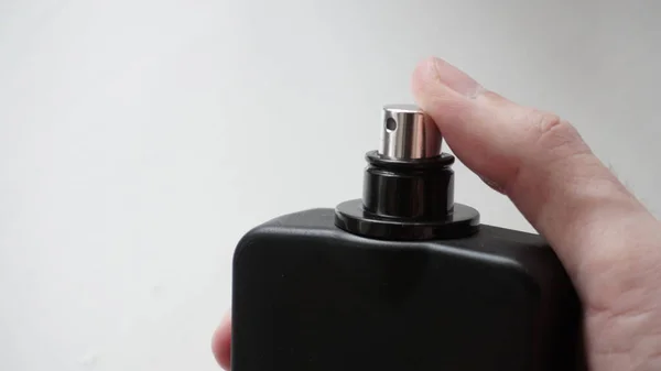 Black perfume bottle in hand