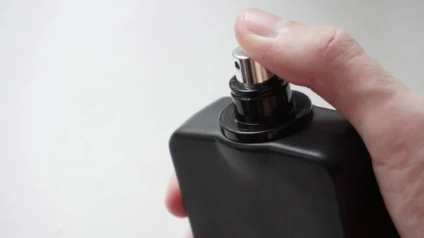 Black perfume bottle in hand