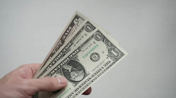 Three American one dollar bills in a man\'s hand