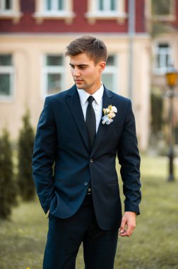 Takım elbiseli yakışıklı damat, mavi ceketli beyaz gömlek ve düğün gününde kravat.