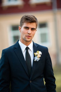 Takım elbiseli yakışıklı damat sokakta poz veriyor.