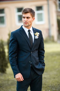 Takım elbiseli yakışıklı damat, mavi ceketli beyaz gömlek ve düğün gününde kravat.