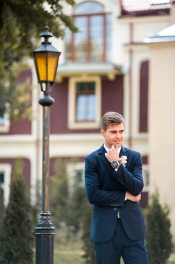 Dışarıda poz veren takım elbiseli yakışıklı bir damat.