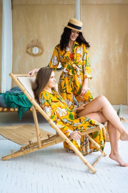 Hasır şapkalı ve kumsalda havlusu olan genç ve güzel kadınlar.