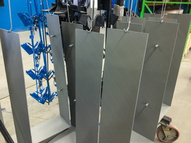 Toz kaplama hattı. Metal paneller, üstteki taşıma hattında askıya alındı. Elektrostatik alanda boyama ürünleri.