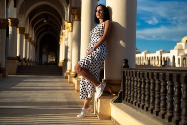 Sokakta yürüyen elbiseli güzel genç bir kadın.