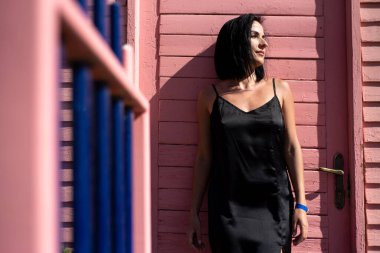 portrait of a beautiful young woman in a black dress and a jacket on a background of a wall