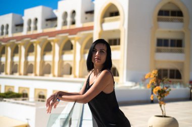 Kumsalda siyah elbiseli güzel bir kadın.