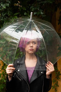 Dışarıda dolaşırken şemsiye tutan neşeli güzel kız. Arkasını dönüp kameraya bakıyor. Gerçek bir zevk ve samimi bir gülümsemeyle..