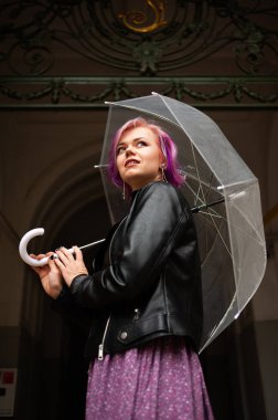 Dışarıda dolaşırken şemsiye tutan neşeli güzel kız. Arkasını dönüp kameraya bakıyor. Gerçek bir zevk ve samimi bir gülümsemeyle..