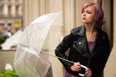 Dışarıda dolaşırken şemsiye tutan neşeli güzel kız. Arkasını dönüp kameraya bakıyor. Gerçek bir zevk ve samimi bir gülümsemeyle..