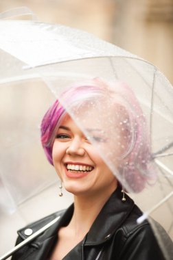 Kurumuş ve korunmuş hissediyorum. Sokakta dururken şemsiye taşıyan ve gülümseyen çekici genç bir kadın.