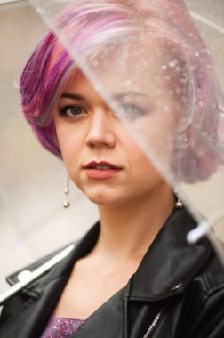 Dışarıda dolaşırken şemsiye tutan neşeli güzel kız. Arkasını dönüp kameraya bakıyor. Gerçek bir zevk ve samimi bir gülümsemeyle..