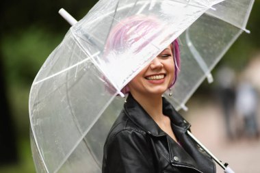 Dışarıda dolaşırken şemsiye tutan neşeli güzel kız. Arkasını dönüp kameraya bakıyor. Gerçek bir zevk ve samimi bir gülümsemeyle..