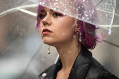 Dışarıda dolaşırken şemsiye tutan neşeli güzel kız. Arkasını dönüp kameraya bakıyor. Gerçek bir zevk ve samimi bir gülümsemeyle..