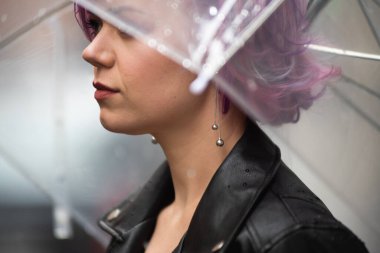 Kurumuş ve korunmuş hissediyorum. Sokakta dururken şemsiye taşıyan ve gülümseyen çekici genç bir kadın.