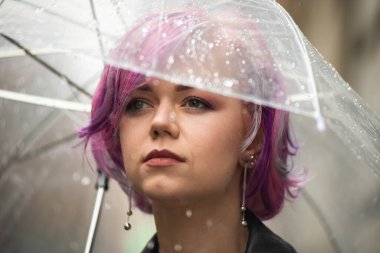 Dışarıda dolaşırken şemsiye tutan neşeli güzel kız. Arkasını dönüp kameraya bakıyor. Gerçek bir zevk ve samimi bir gülümsemeyle..