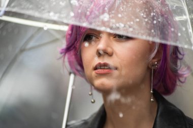 Kurumuş ve korunmuş hissediyorum. Sokakta dururken şemsiye taşıyan ve gülümseyen çekici genç bir kadın.