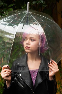 Kurumuş ve korunmuş hissediyorum. Sokakta dururken şemsiye taşıyan ve gülümseyen çekici genç bir kadın.