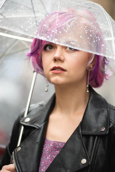 Yağmurlu bir gün. Parlak şemsiyeli gülümseyen kadın