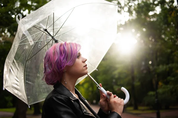 Kurumuş ve korunmuş hissediyorum. Sokakta dururken şemsiye taşıyan ve gülümseyen çekici genç bir kadın.