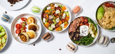 Beyaz arka plandaki et, sebze ve tatlılardan oluşan şenlikli yemekler. Menü ayarlandı.