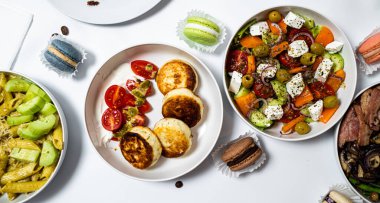 Beyaz arka plandaki et, sebze ve tatlılardan oluşan şenlikli yemekler. Menü ayarlandı.