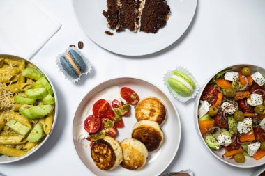 Beyaz arka plandaki et, sebze ve tatlılardan oluşan şenlikli yemekler. Menü ayarlandı.